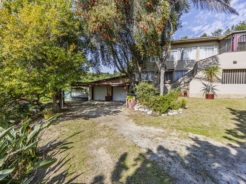 Front exterior view of the property featuring a double garage, driveway, and established garden surroundings.