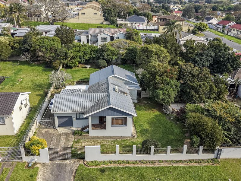 Aerial view of a residential property featuring a metal roof, solar geyser, private garden, and driveway access within a suburban neighborhood.