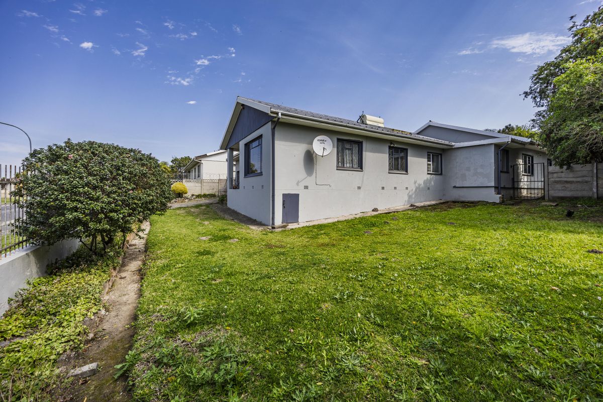Rear view of the house featuring a lawn, solar geyser, and secure boundary walling.