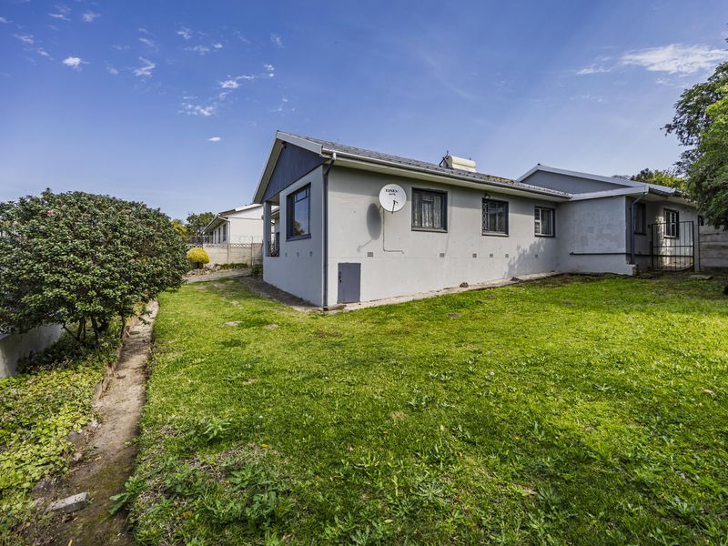 Rear view of the house featuring a lawn, solar geyser, and secure boundary walling.