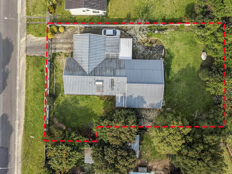 Aerial view of the property showing the house footprint, corrugated metal roof, surrounding garden, and driveway access from the street.