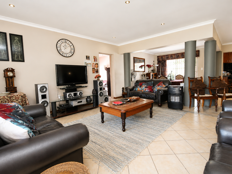 Spacious open-plan living area featuring ceramic floor tiles, recessed downlighting, and structural columns connecting to the adjacent dining and kitchen space.