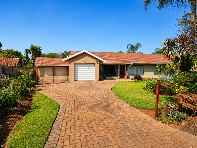 A well-maintained single-story home featuring a brick-paved driveway, a single garage, and a neatly landscaped front garden.