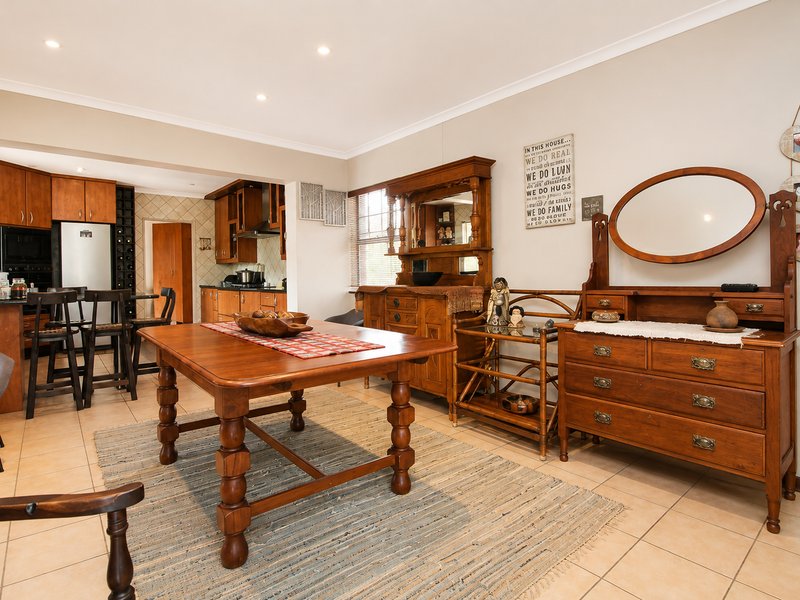 Open-plan dining and kitchen area featuring tiled flooring, wooden cabinetry, and recessed lighting, creating a functional and connected living space.