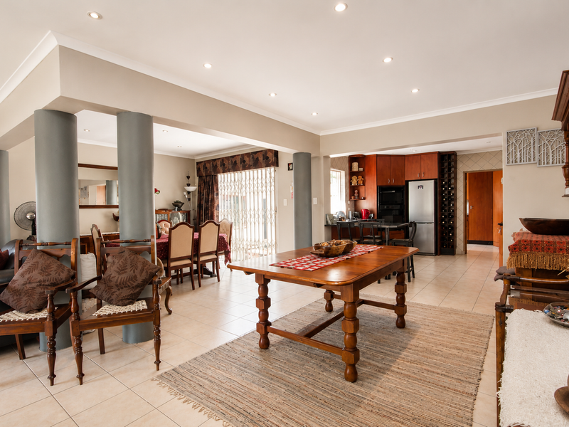 Spacious open-plan living and dining area featuring ceramic floor tiles, recessed lighting, and a functional kitchen with integrated cabinetry and wine storage.
