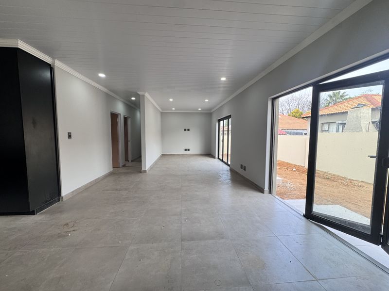 Spacious open-plan living area featuring large format floor tiles, recessed lighting, and sliding glass doors providing direct access to the outdoor space.
