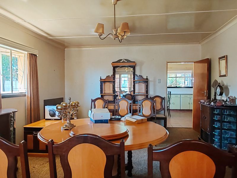 A spacious dining room featuring a classic layout with access to an adjacent kitchen area, offering potential for modernization and updated interior finishes.
