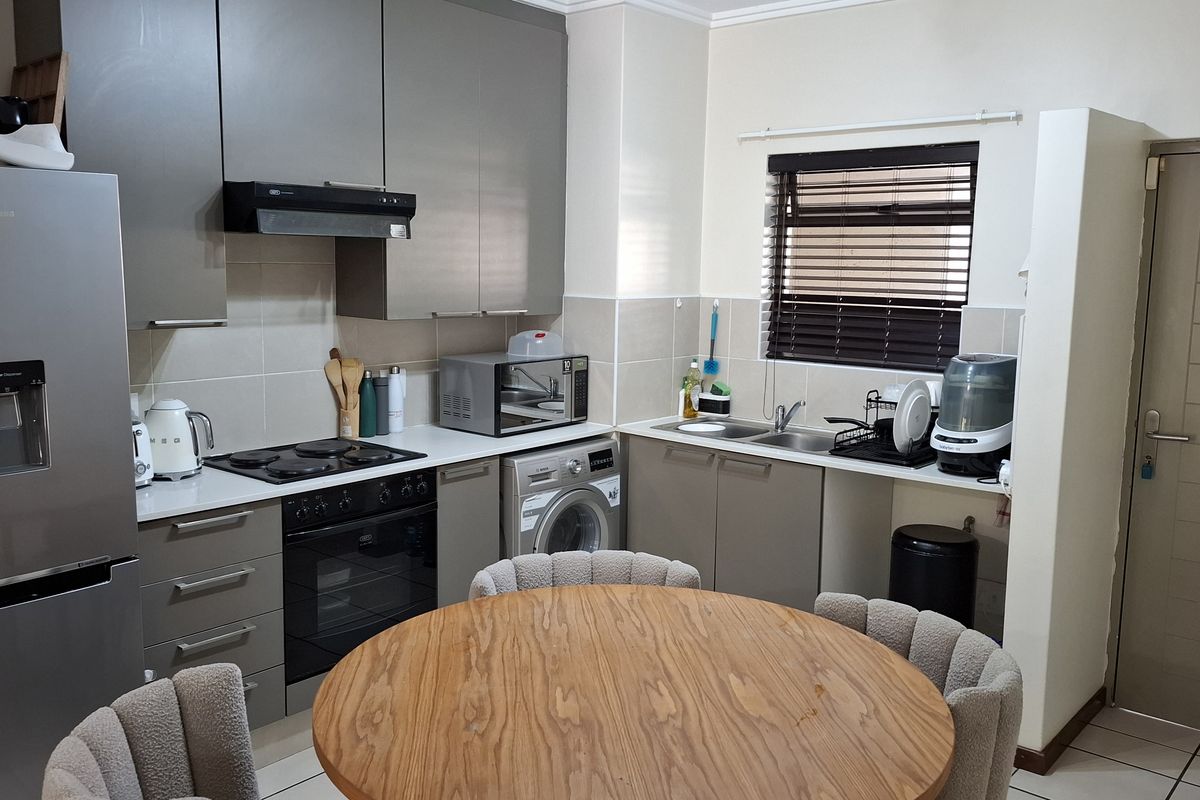 Modern kitchen featuring grey cabinetry, built-in oven and hob, extractor fan, and a double sink with tiled backsplash and flooring.