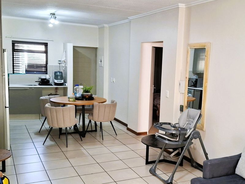 Open-plan living and dining area featuring tiled flooring and a functional kitchen space with built-in cabinetry.