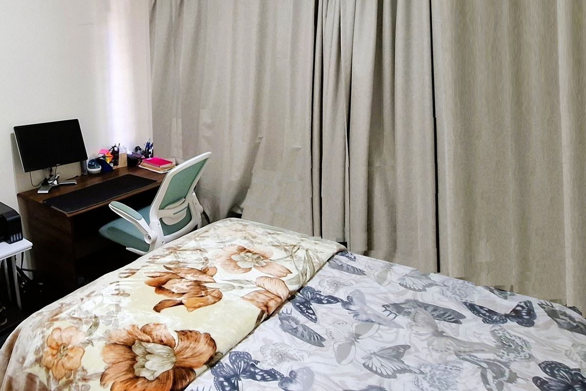 A bedroom featuring floor-to-ceiling curtains and neutral wall finishes, providing a functional space for rest and work.