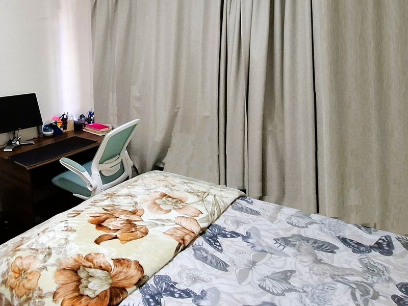 A bedroom featuring floor-to-ceiling curtains and neutral wall finishes, providing a functional space for rest and work.