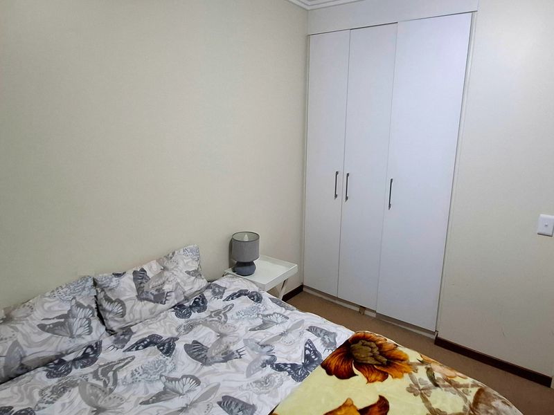 A functional bedroom featuring a white built-in wardrobe and neutral wall finishes, providing a clean and simple space.