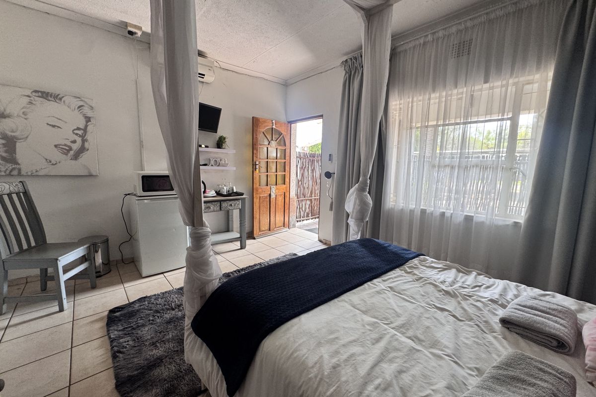A bedroom featuring tiled flooring, an air conditioning unit, and direct access to an outdoor area through a timber door.