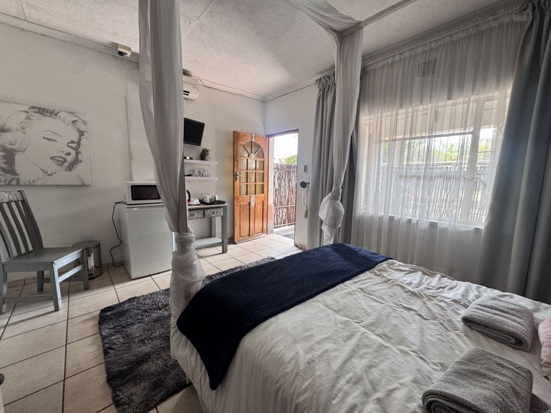 A bedroom featuring tiled flooring, an air conditioning unit, and direct access to an outdoor area through a timber door.