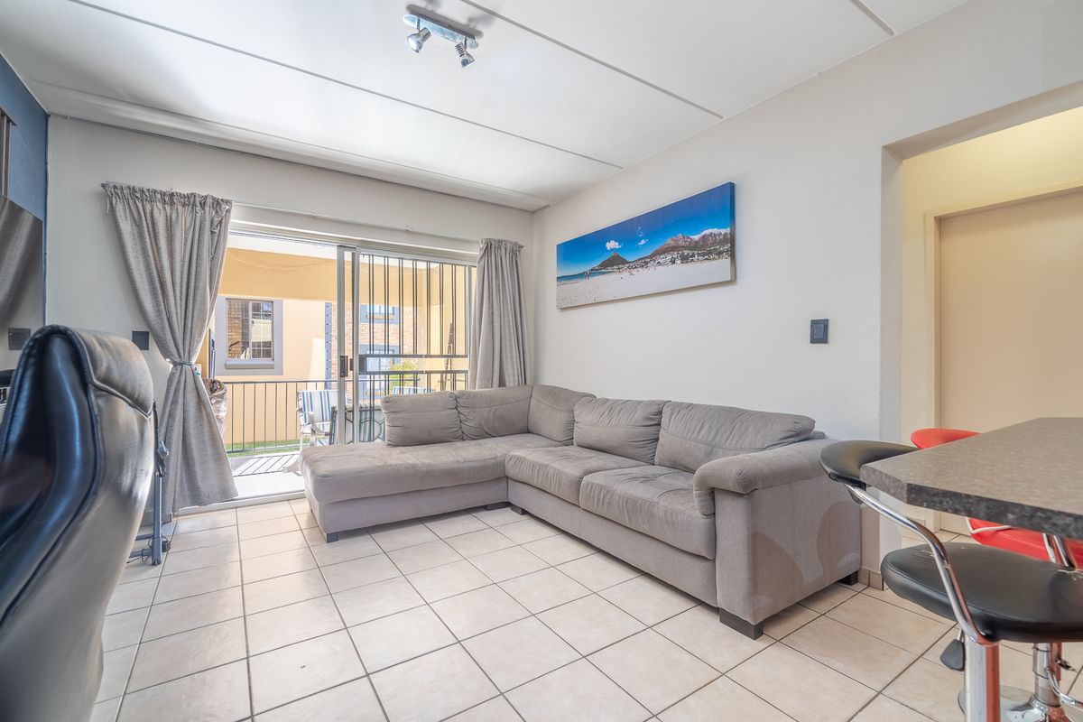 A living room featuring tiled flooring and a sliding glass door that opens onto a balcony, providing natural light and access to outdoor space.