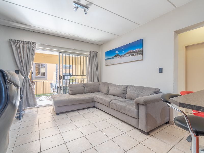 A living room featuring tiled flooring and a sliding glass door that opens onto a balcony, providing natural light and access to outdoor space.