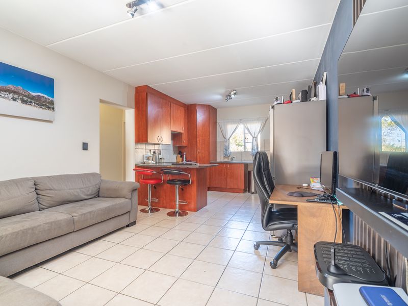 Open-plan living area featuring tiled flooring and a functional kitchen with built-in cabinetry and a breakfast bar.