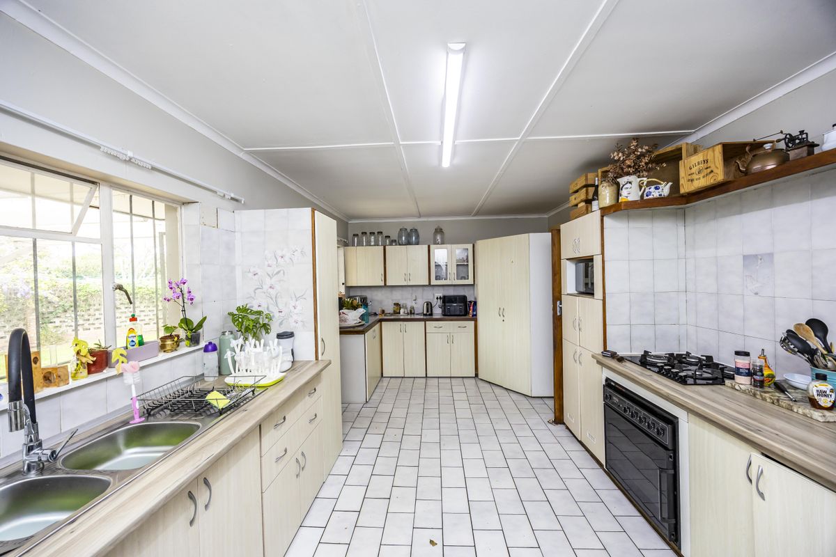 Functional kitchen featuring built-in cabinetry, gas hob, integrated oven, double bowl sink, and tiled splashbacks with ample counter space.