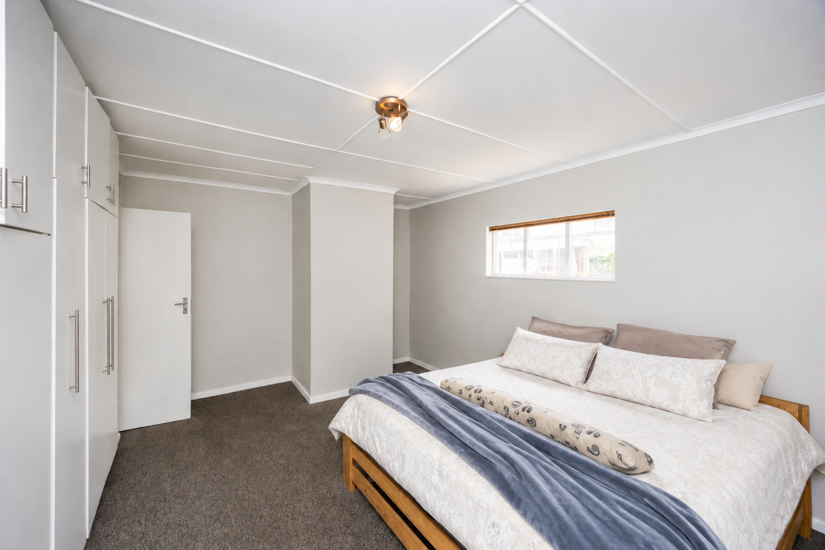 A well-maintained bedroom featuring neutral walls, carpeted flooring, and ample built-in cupboard storage space.