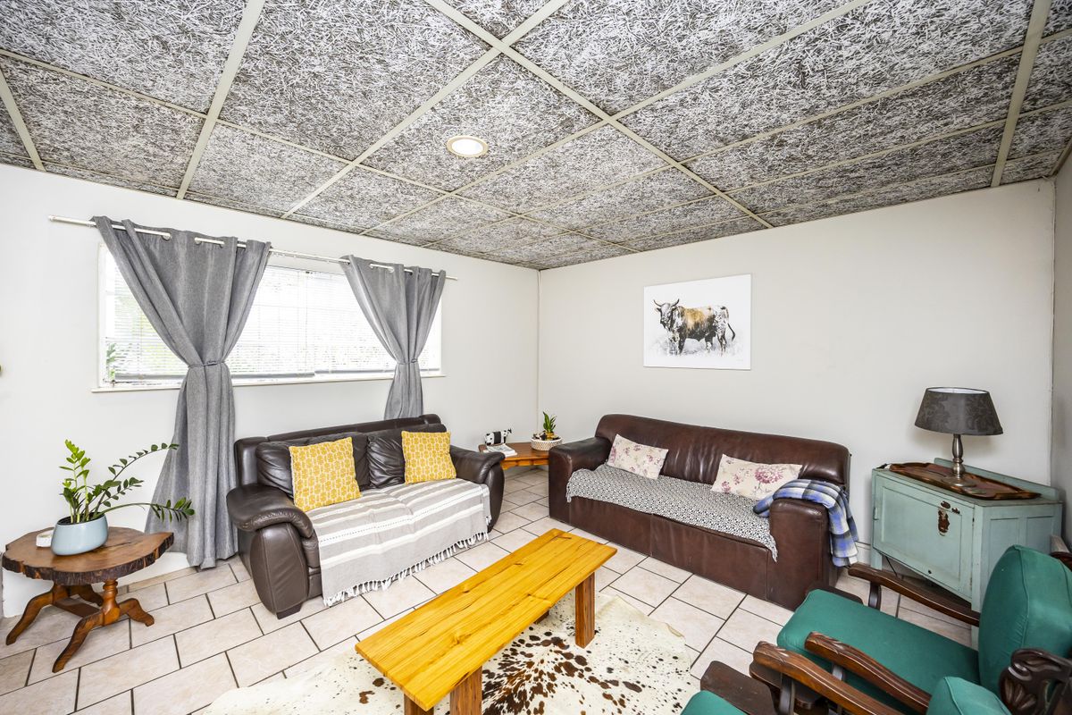 A living room featuring ceramic floor tiles and a distinctive acoustic tile ceiling with recessed lighting.