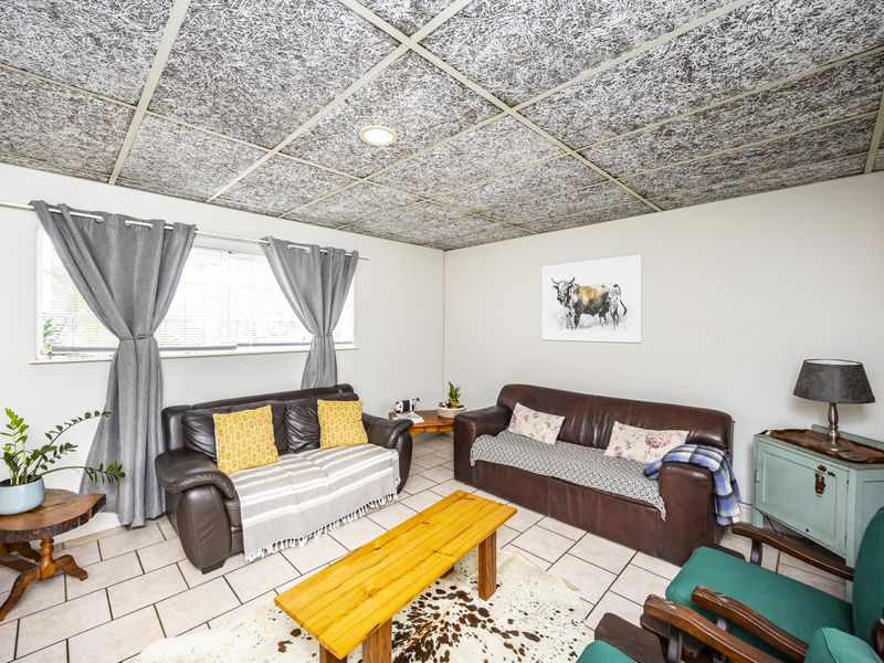 A living room featuring ceramic floor tiles and a distinctive acoustic tile ceiling with recessed lighting.