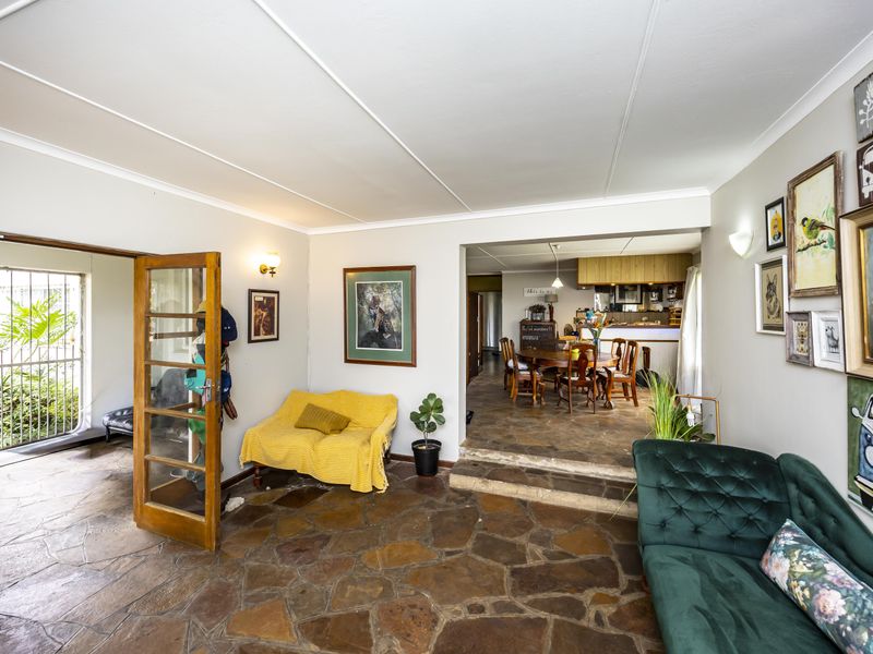Open-plan living and dining area featuring rustic flagstone flooring, a raised dining section, and direct access to an outdoor patio area.