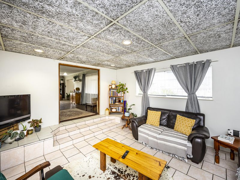 Living room featuring tiled flooring, a raised platform area, and a distinctive acoustic tile ceiling with recessed lighting.