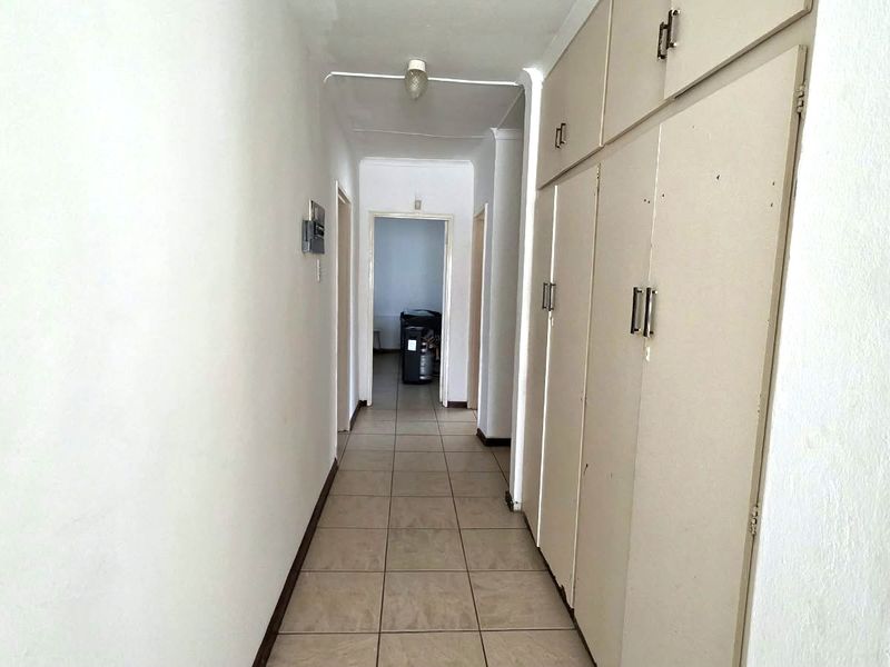 A functional hallway featuring tiled flooring and extensive built-in storage cupboards, providing practical access to other areas of the home.