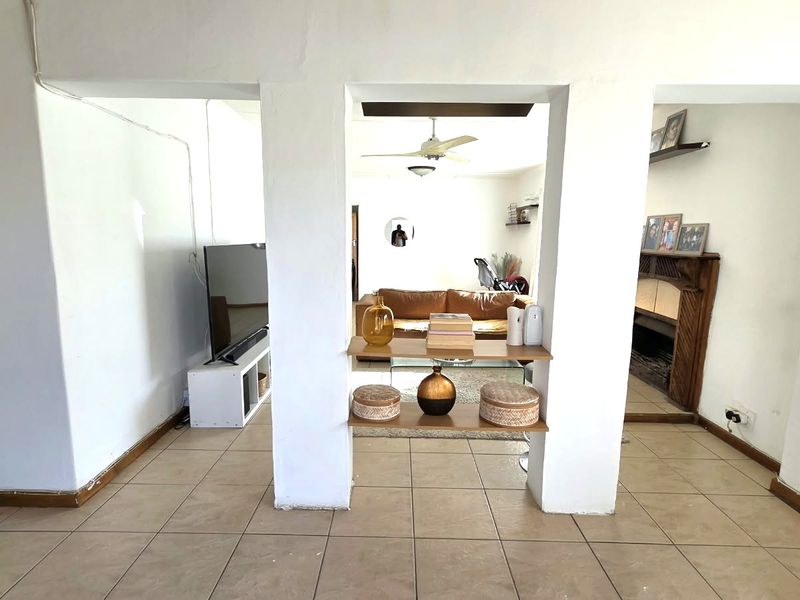 Open-plan living area featuring tiled flooring, a built-in fireplace, and structural pillars separating the space.