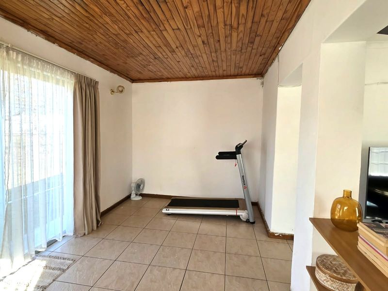 Living area featuring tiled flooring, a timber tongue and groove ceiling, and a large sliding glass door providing access to the exterior.