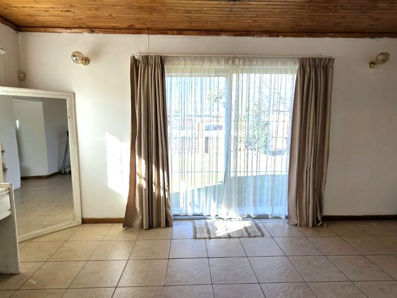 Spacious living area featuring tiled flooring, a timber-clad ceiling, and a large sliding glass door providing access to the exterior.