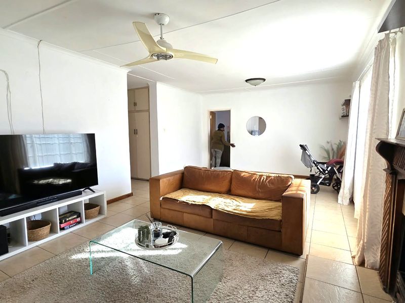 A living room featuring tiled flooring, a ceiling fan, and a built-in fireplace, offering a functional and comfortable living space.