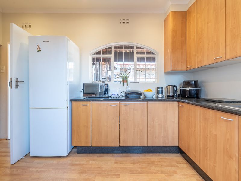 A functional kitchen featuring light wood laminate cabinetry, dark granite countertops, and an arched window, providing a practical workspace with a classic layout.