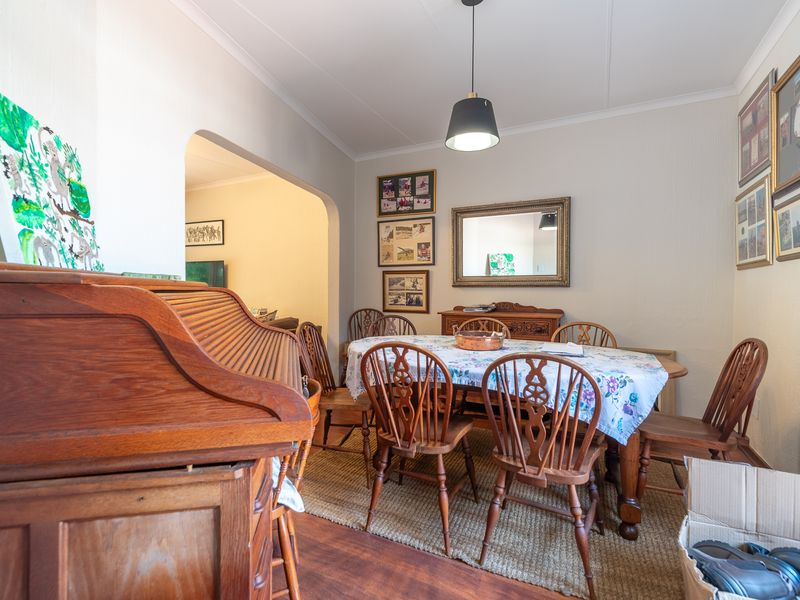 A dining room featuring a central pendant light and an open archway leading to an adjacent living space.