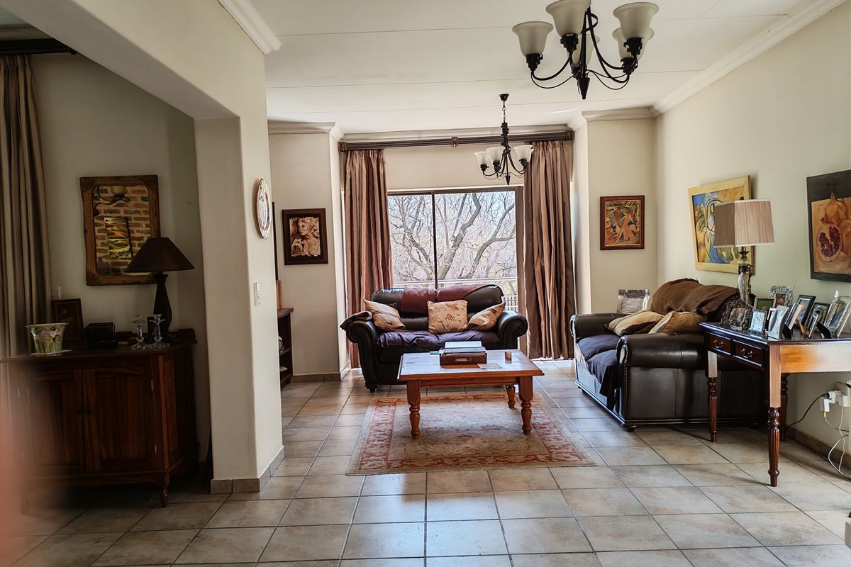 Spacious living room featuring tiled flooring, coved cornicing, and a sliding glass door providing natural light and access to the exterior.