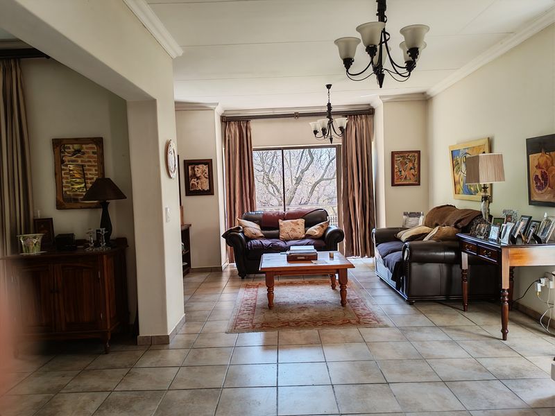 Spacious living room featuring tiled flooring, coved cornicing, and a sliding glass door providing natural light and access to the exterior.