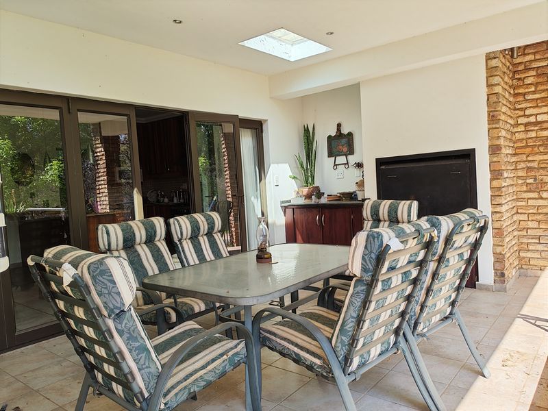 Covered patio featuring a built-in braai, skylight, and tiled flooring, providing a functional outdoor entertainment space with direct access to the interior.