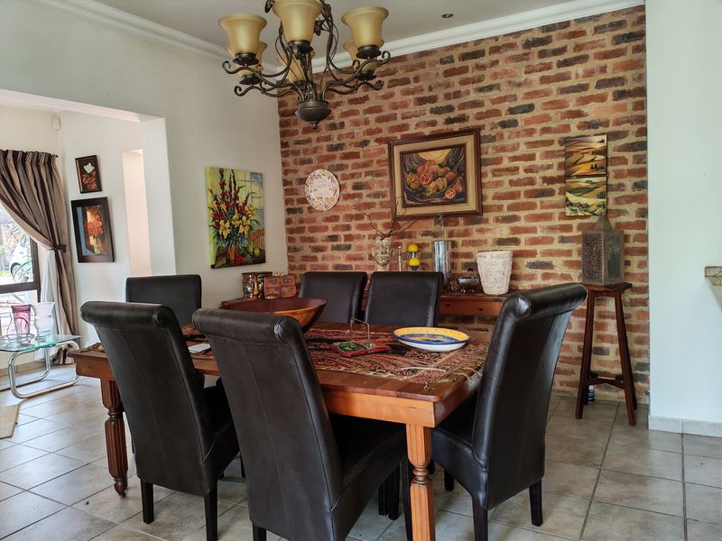 A dining room featuring an exposed brick feature wall, tiled flooring, and a decorative chandelier, creating a warm and traditional atmosphere.