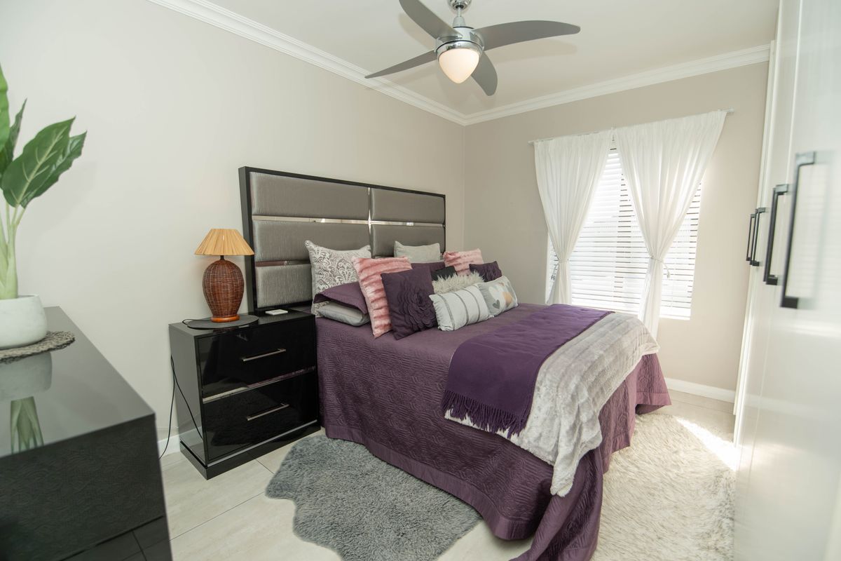 A well-maintained bedroom featuring tiled flooring, crown molding, a ceiling fan, and built-in wardrobe storage.