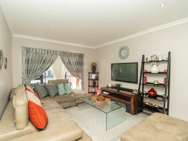 A well-maintained living room featuring recessed downlighting, crown molding, and a sliding glass door providing access to the balcony.