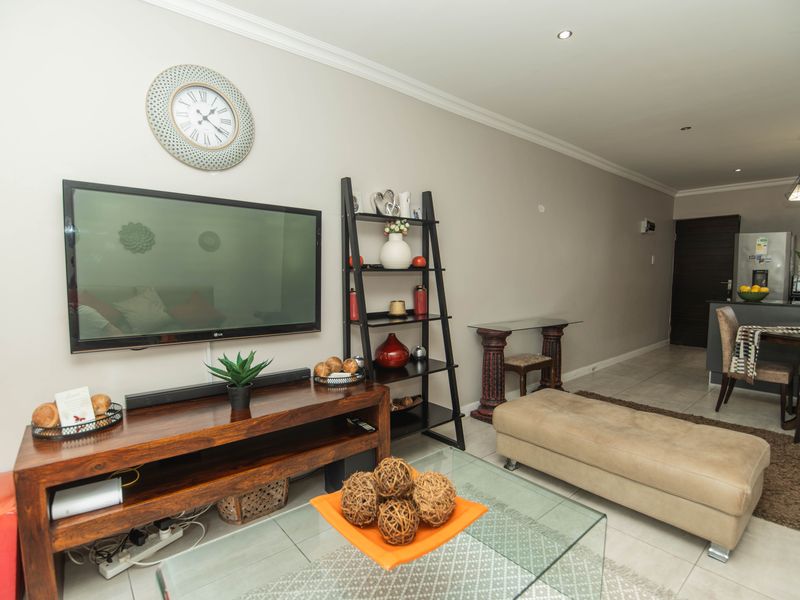 Open plan living and dining area featuring tiled flooring, recessed downlights, and a modern kitchen layout with pendant lighting.