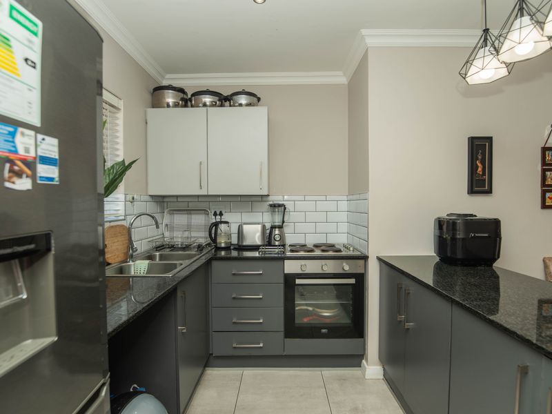 Modern kitchen featuring dark grey cabinetry, granite countertops, subway tile backsplash, and integrated stainless steel oven and hob.