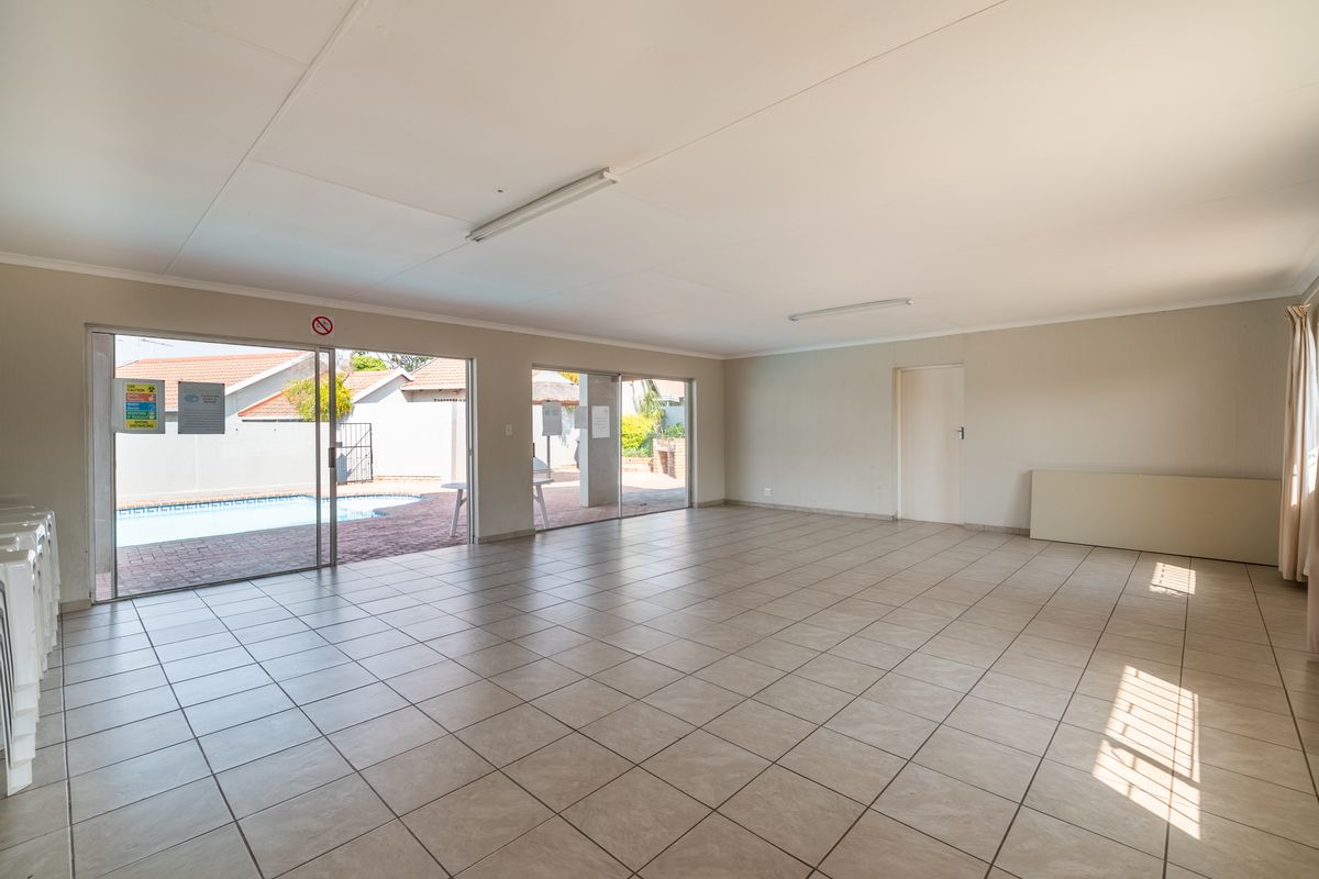 Spacious, empty living area featuring neutral tiled flooring and large sliding glass doors providing direct access to the outdoor pool area.