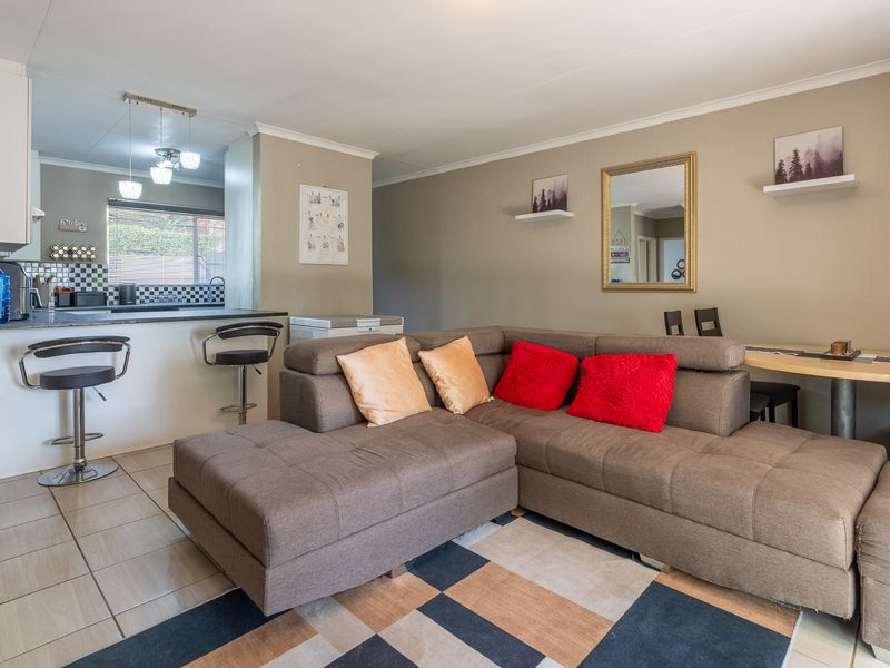 Open plan living area featuring a breakfast bar, tiled flooring, and neutral wall tones, seamlessly connecting the kitchen and lounge space.
