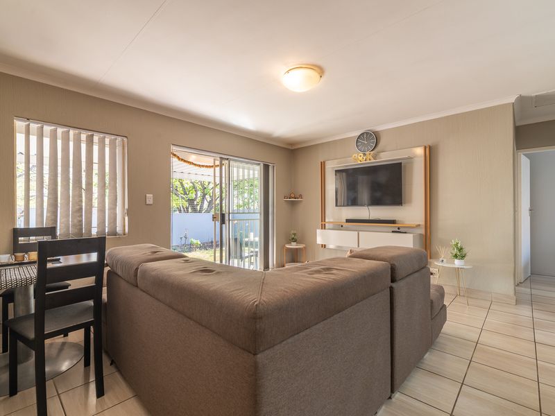 Open plan living area featuring tiled flooring, a built-in media console, and sliding glass doors providing access to the outdoor space.