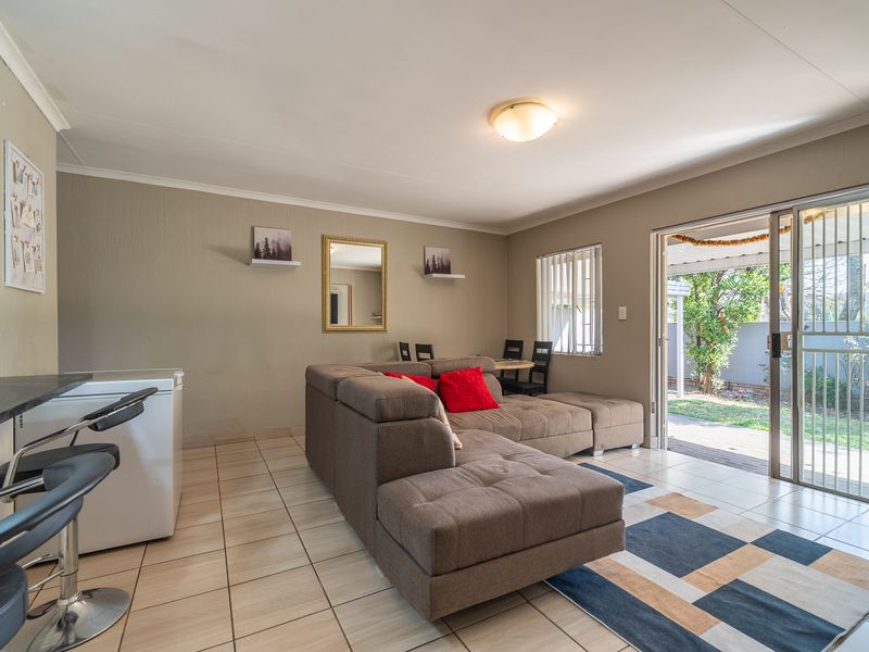 Open plan living area featuring tiled flooring, a breakfast counter, and sliding glass doors providing direct access to the outdoor patio and garden.