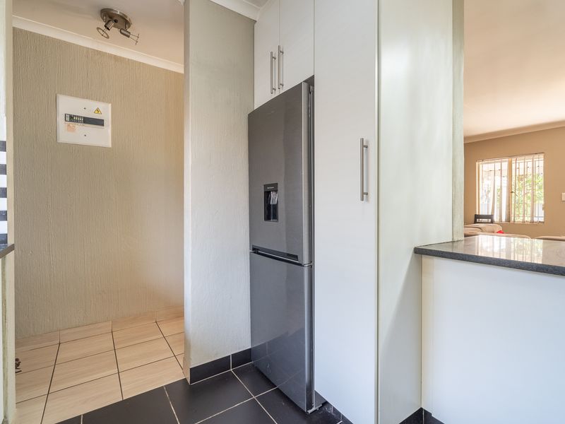 A functional kitchen area featuring built-in cabinetry, granite countertops, and tiled flooring, with a clear view into the adjacent living space.