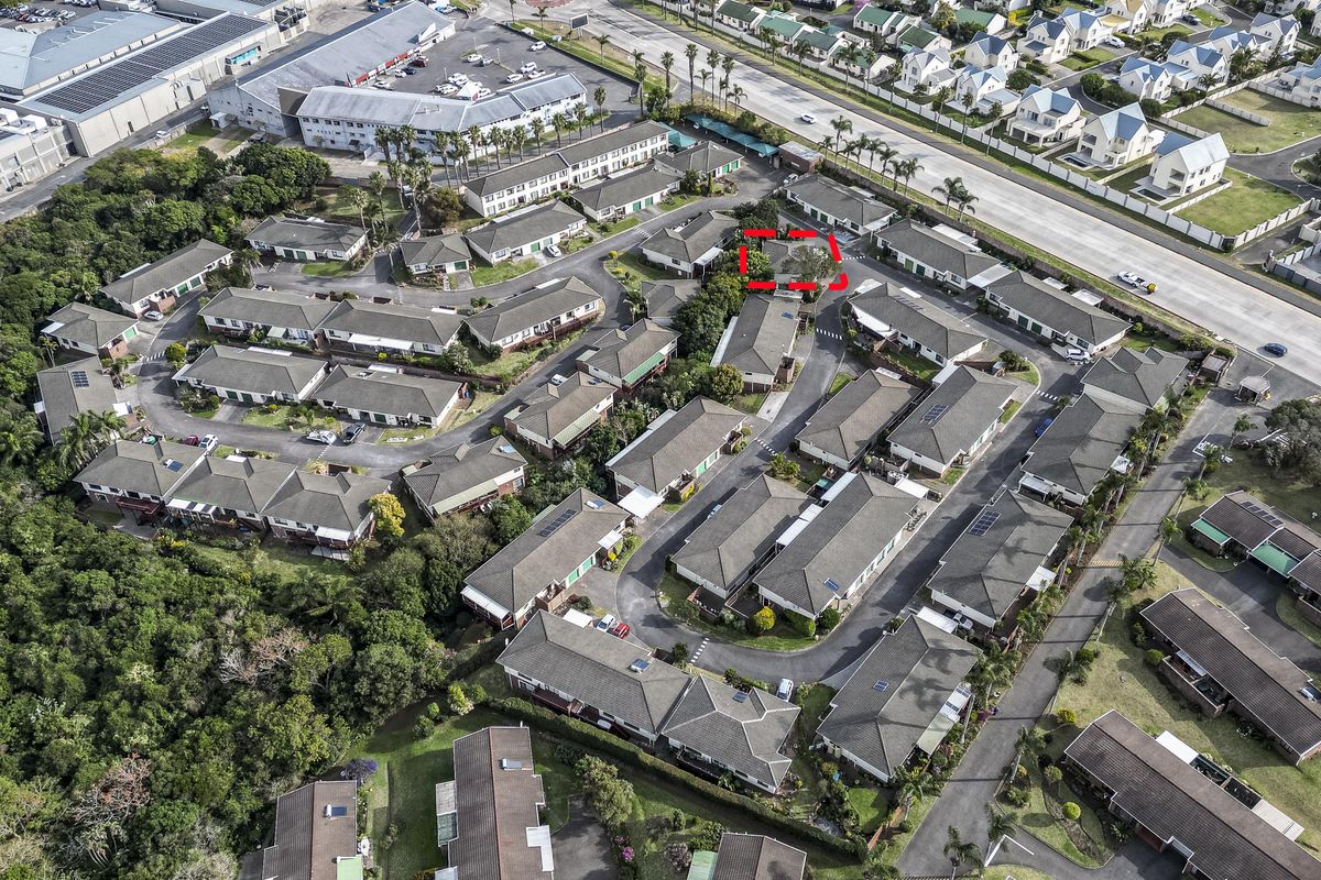 Aerial view of a residential housing complex featuring multiple units with tiled roofs, paved driveways, and established communal landscaping.