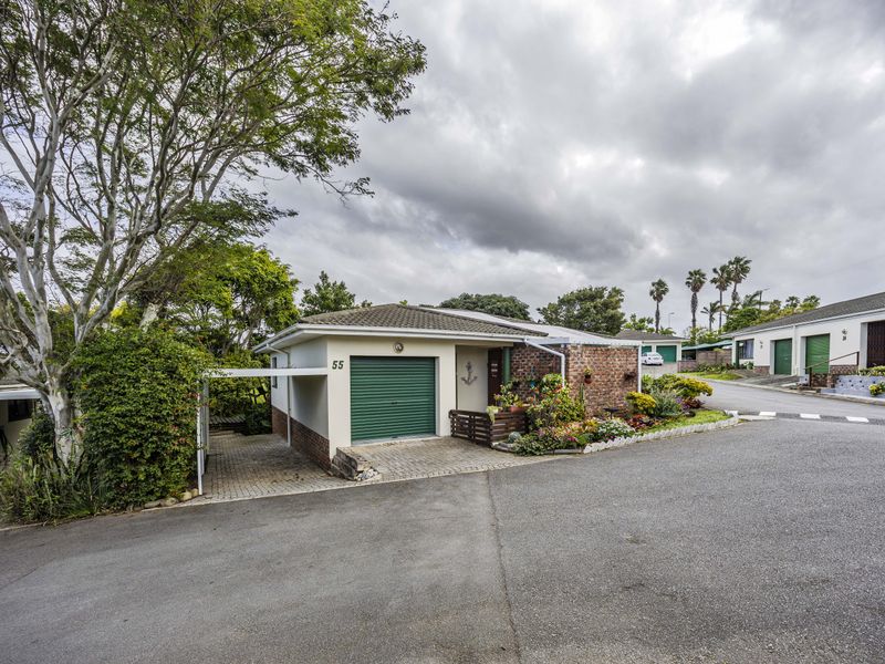 Front exterior view of a residential property featuring a single garage, attached carport, and paved driveway with established garden beds.