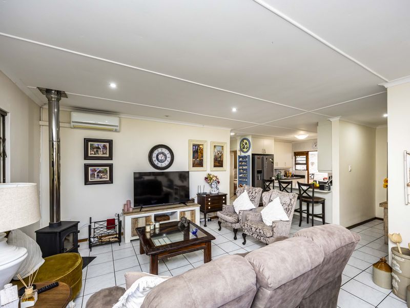 Open-plan living area featuring tiled floors, a freestanding fireplace, and a connected kitchen with a breakfast bar and built-in cabinetry.